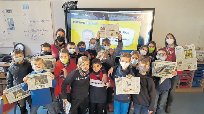 Schulklasse mit Zeitung im Klassenzimmer